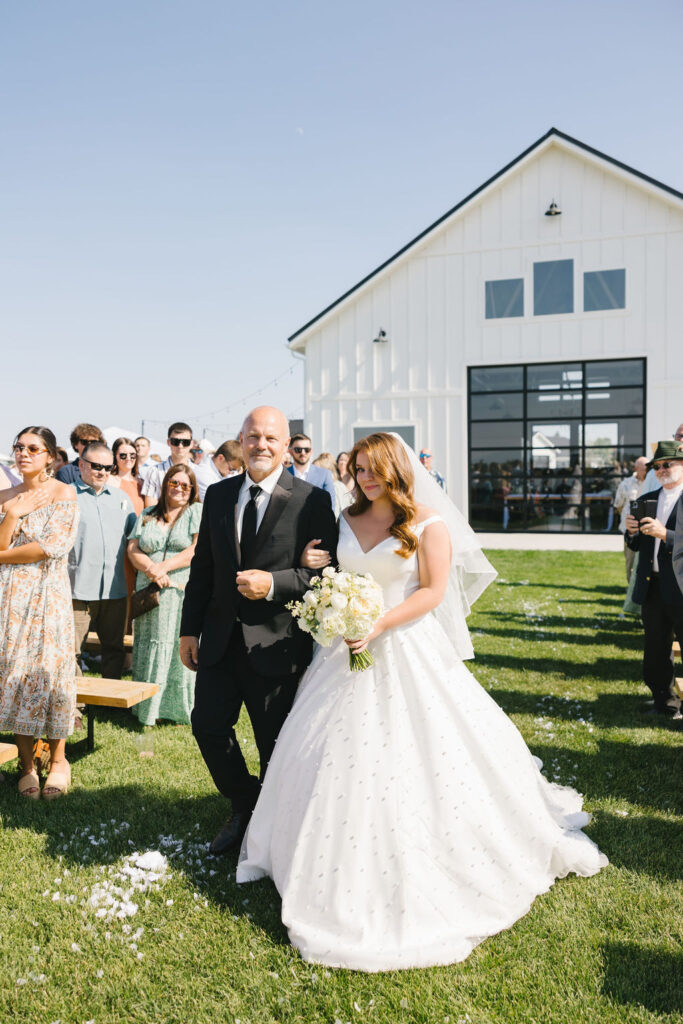 A bride walks down the aisle holding onto dad's arm