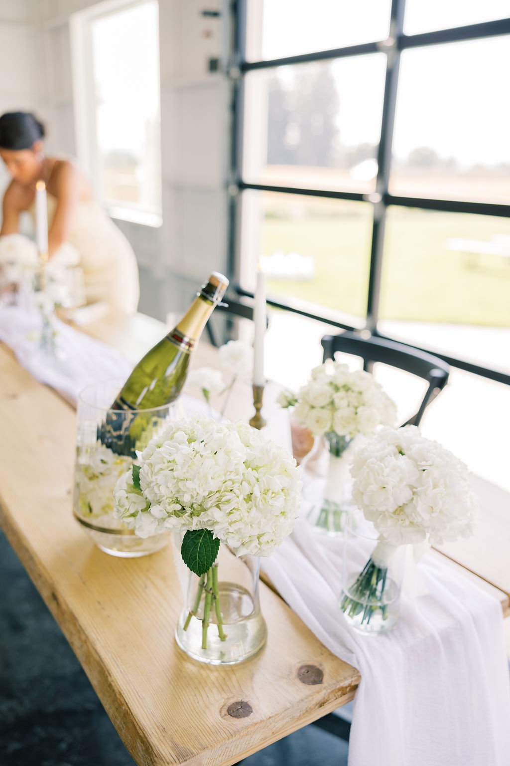 Details of a wedding reception table set up with white linen and flowers and champagne bottle