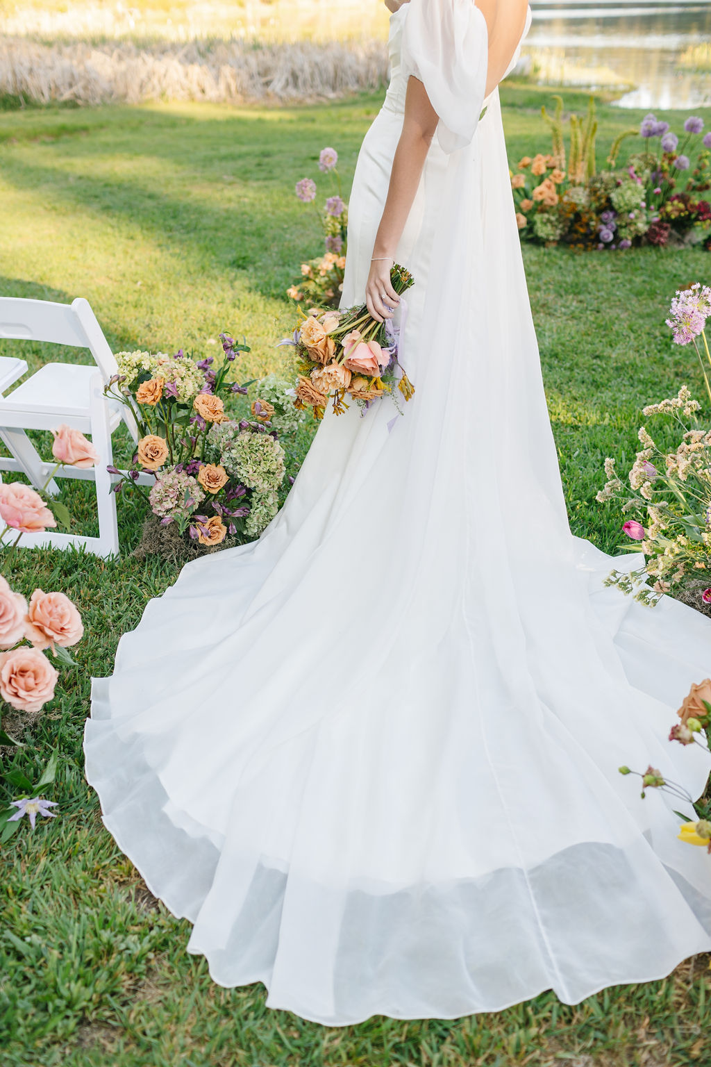 Details of a bride's train spread out in the aisle as she holds her bouquet at lakefront wedding venues coeur d'alene