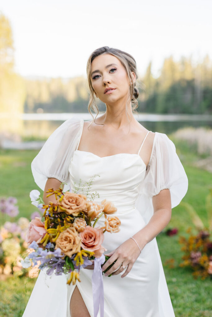 A bride walks by a lake in her ceremony aisle at one of the lakefront wedding venues coeur d'alene