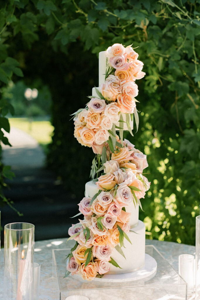 Details of a tall wedding cake covered in pink flowers