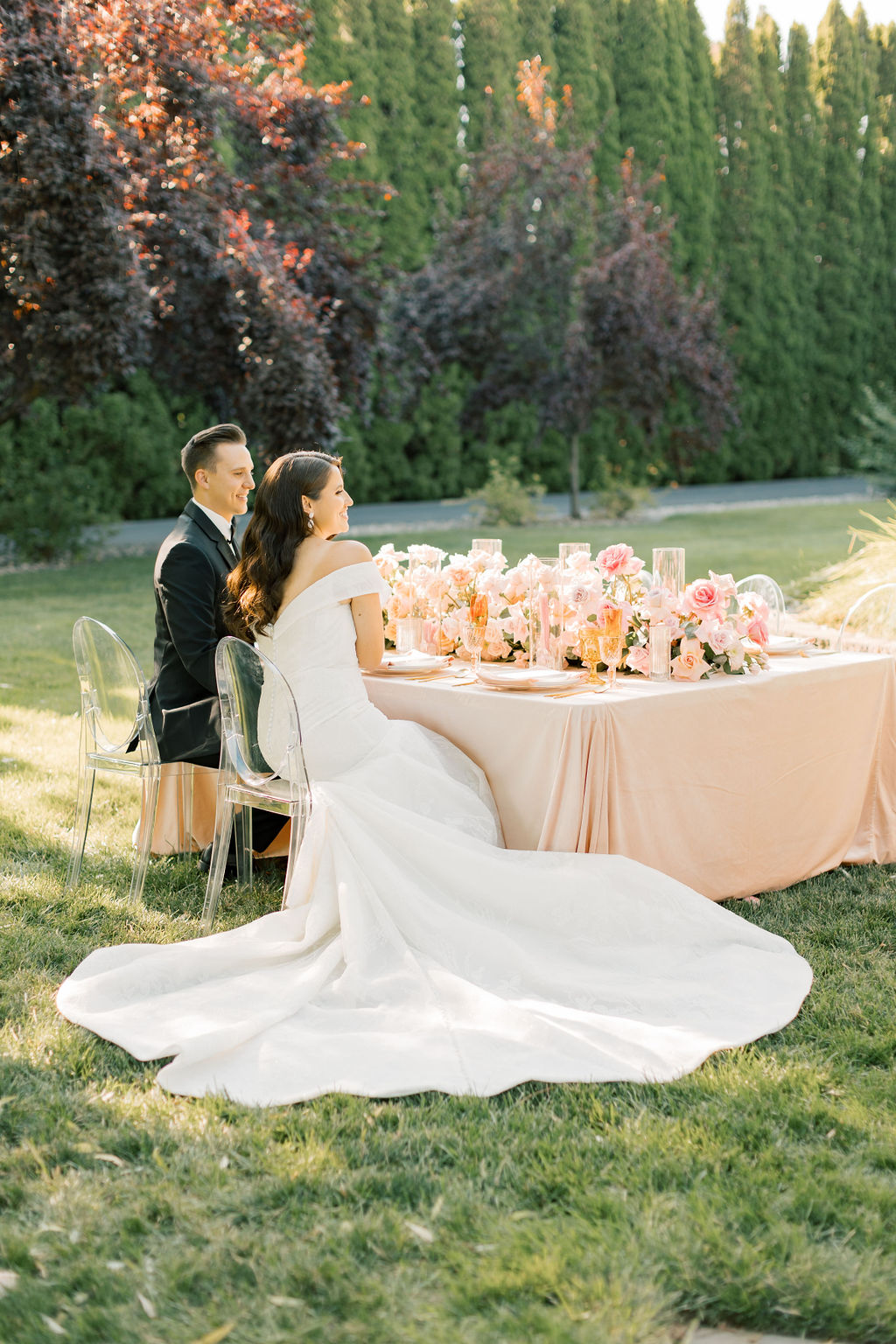 Newlyweds laugh and sit at their head table outside at sunset at the promise garden pasco wedding venue