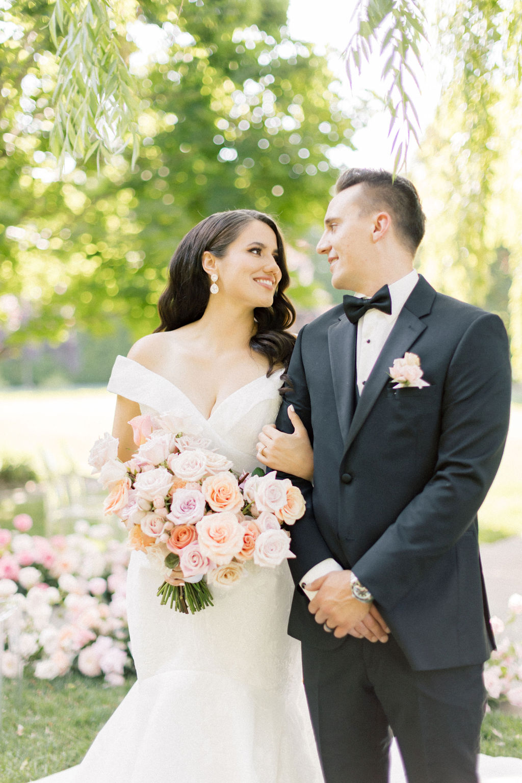 Newlyweds walk arm in arm through the gardens while smiling at each other