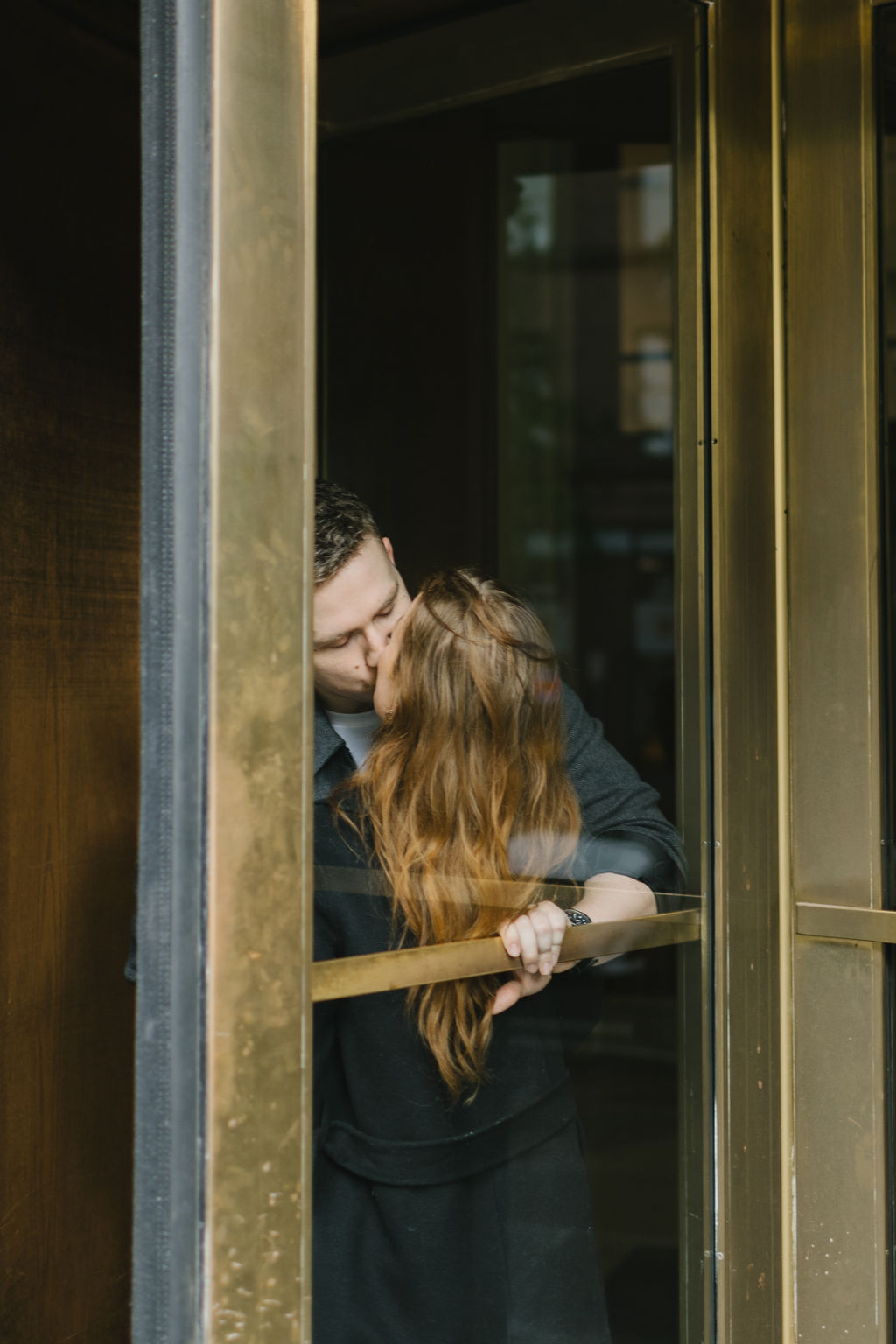 A couple kisses inside a revolving door