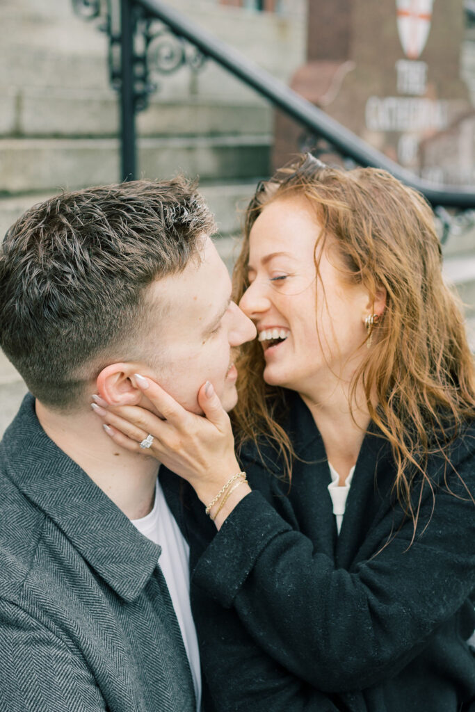 A couple laughs their way into a kiss while sitting on ornate stairs