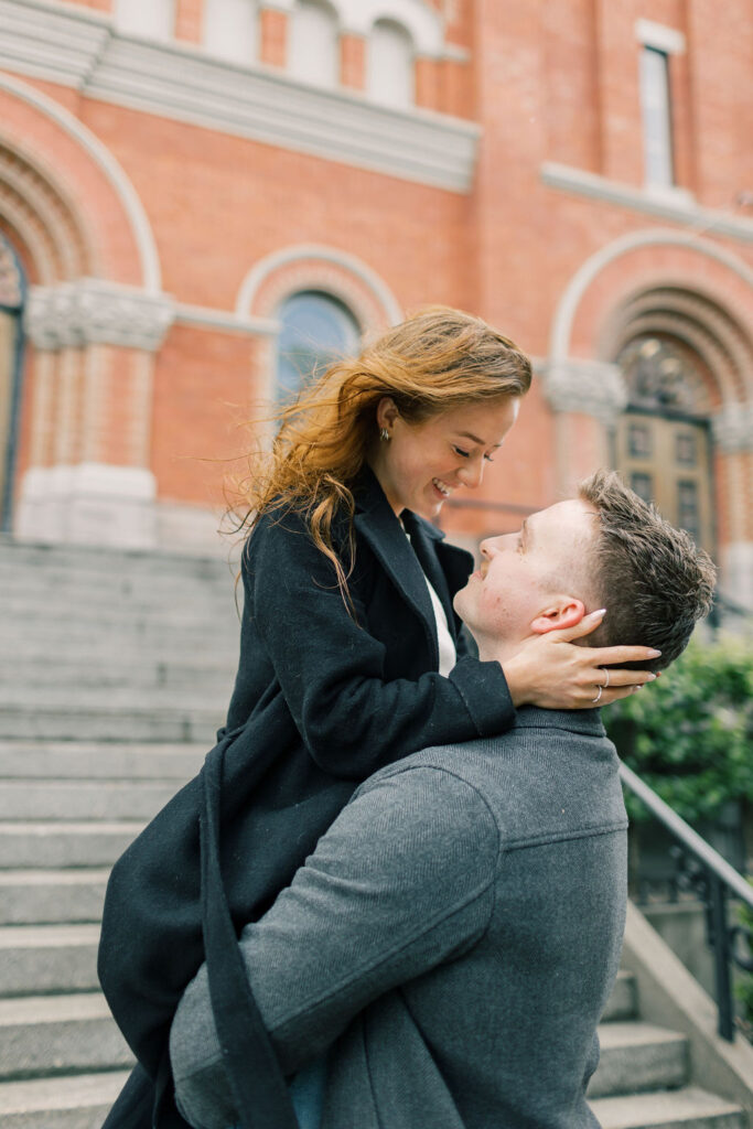 A man lifts his fiancee while standing by some stairs for a spokane engagement photographer