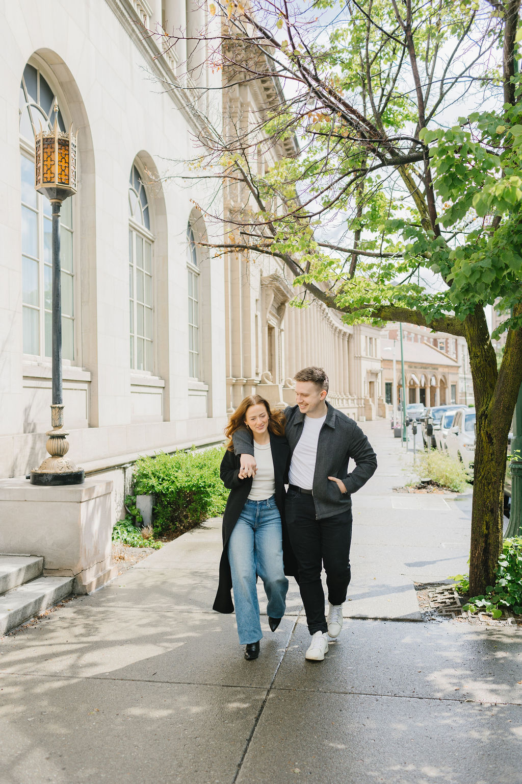 An image from a spokane engagement photographer of a couple with arms around each other while walking in downtown