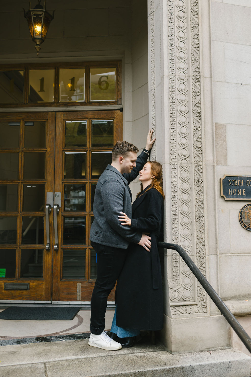 A couple leans on a wall in the entrance to an ornate building for a spokane engagement photographer