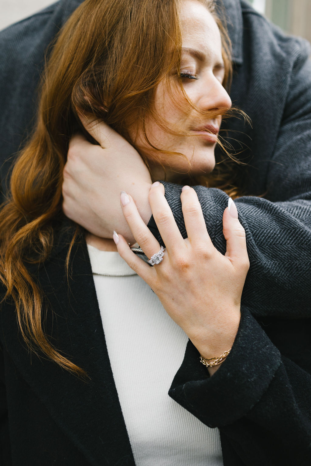 Details of a woman's engagement ring while being hugged by fiancee as guided by a spokane engagement photographer