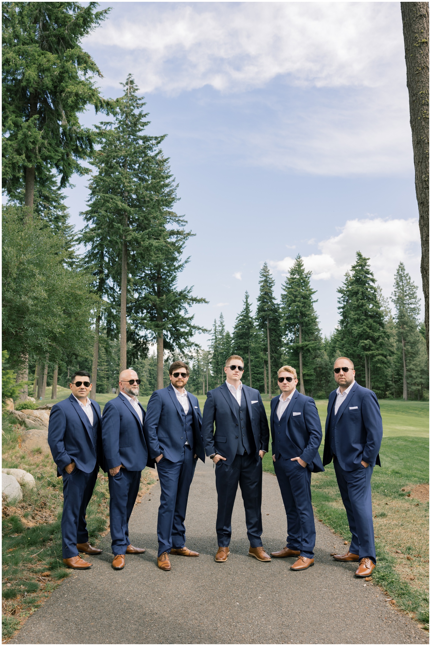 A groom and his groomsmen in matching blue suits and aviators on a sidewalk