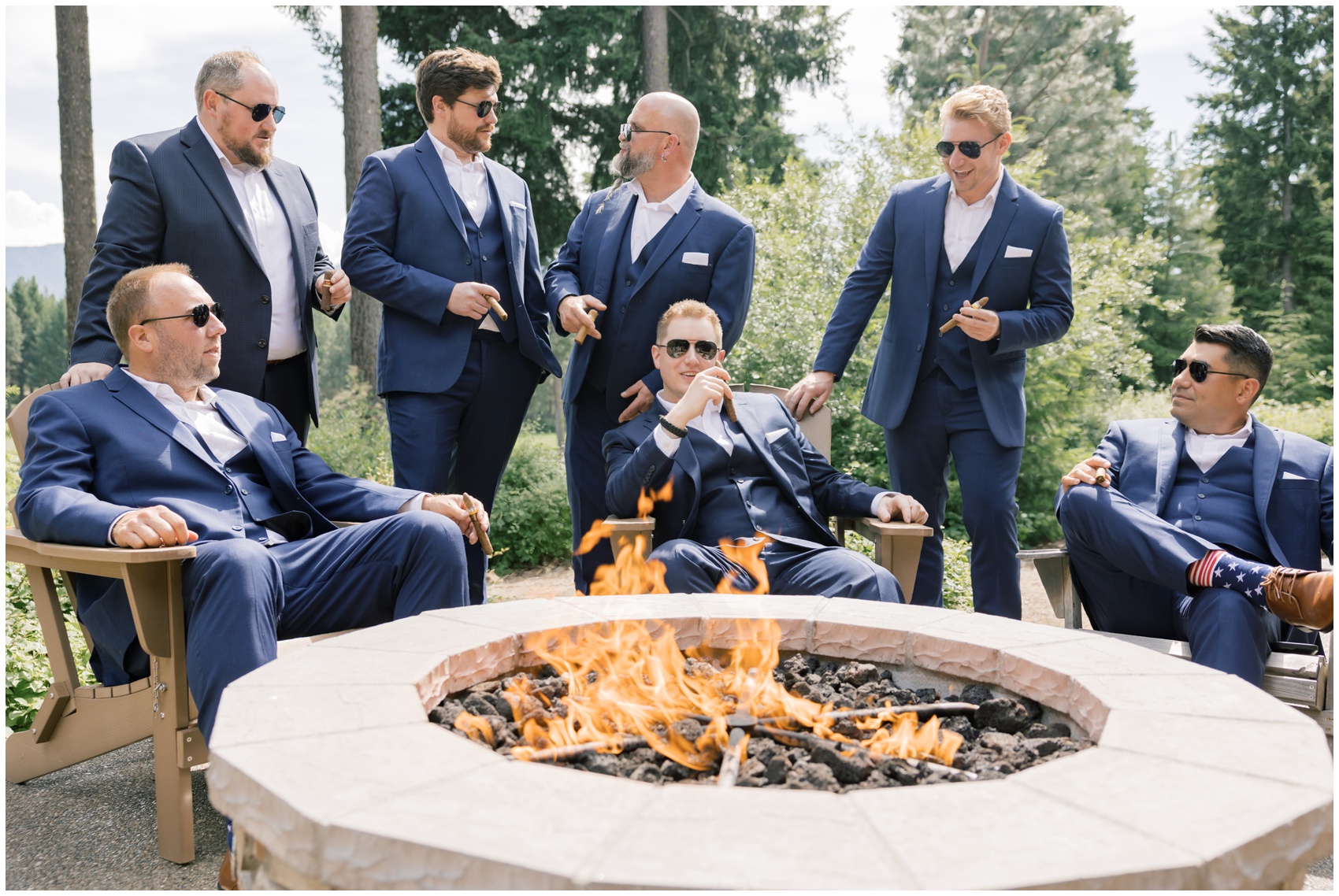 A groom sits in Adirondack chairs around a gas fire with his groomsmen at his suncadia resort wedding