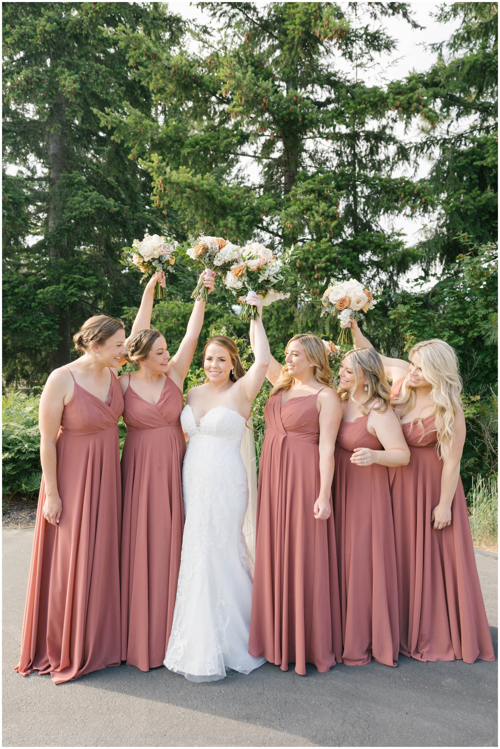 A bride raises her bouquet with her bridesmaids looking at her around her