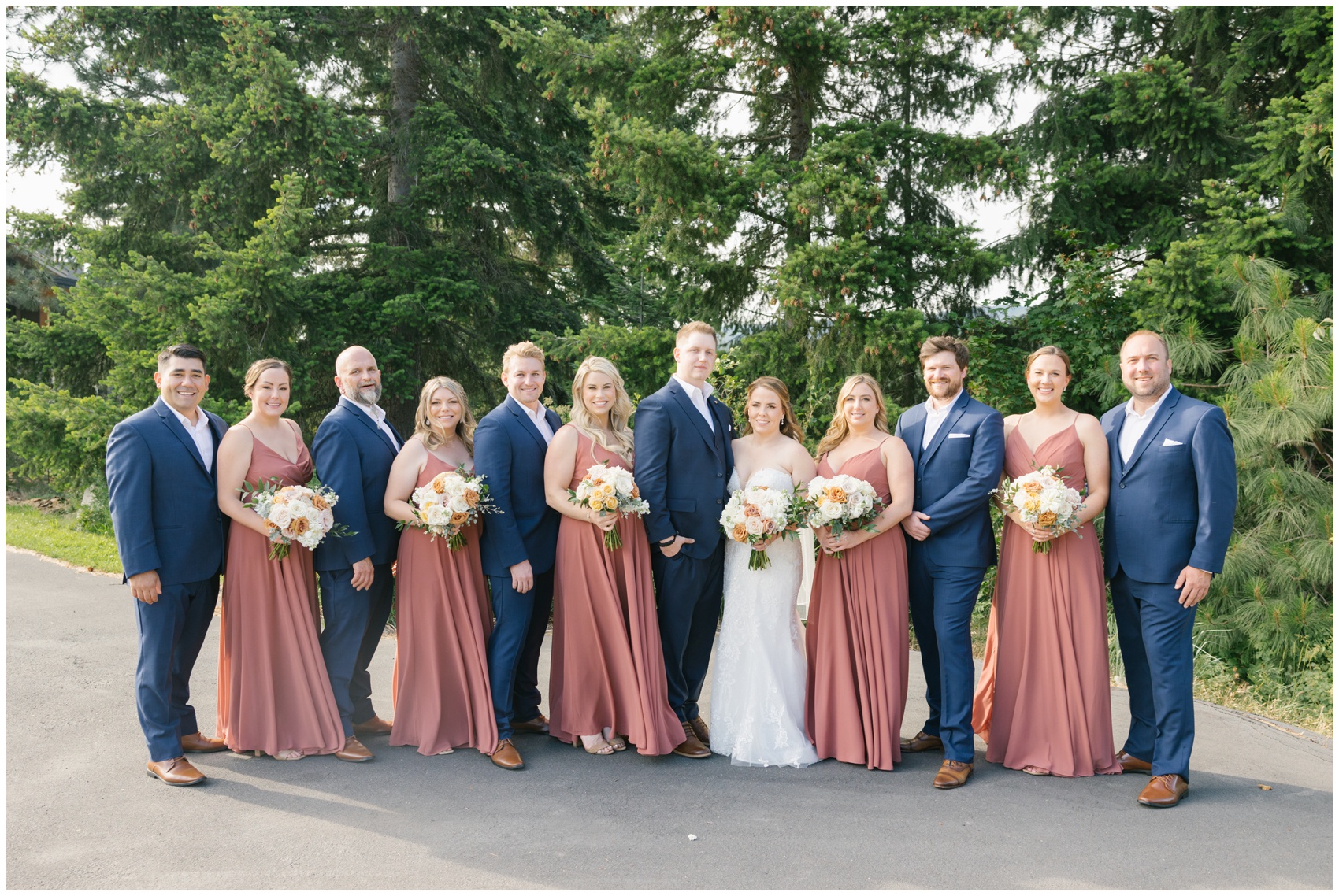 Newlyweds stand in a road with their bridal party smiling at their suncadia resort wedding