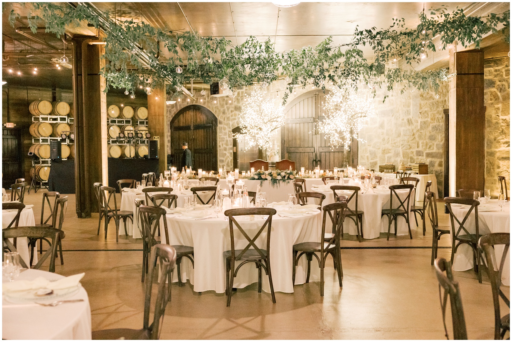 A view of an empty swiftwater cellars wedding reception with hanging greenery and white linen