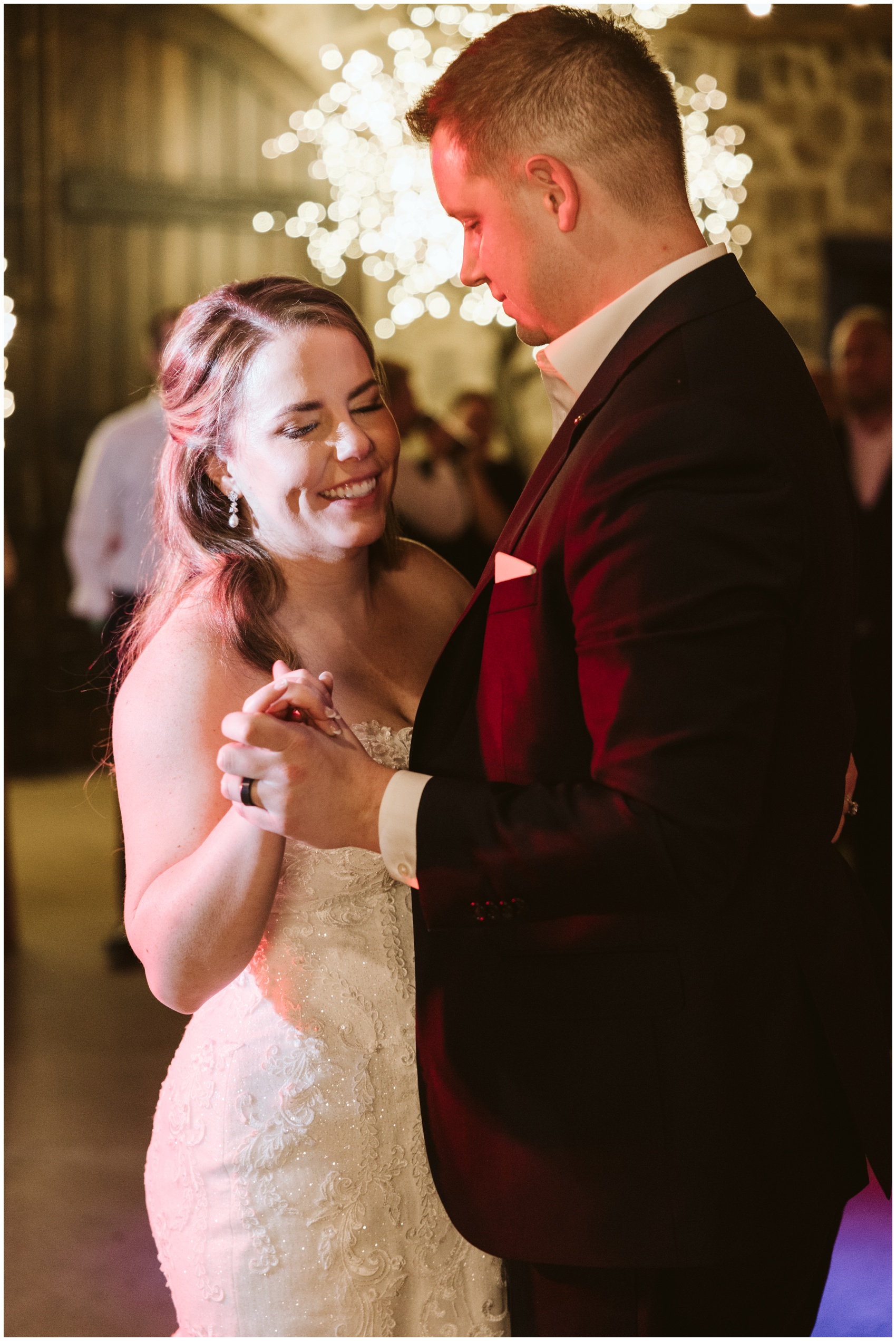 A bride and groom dance while smiling at their reception