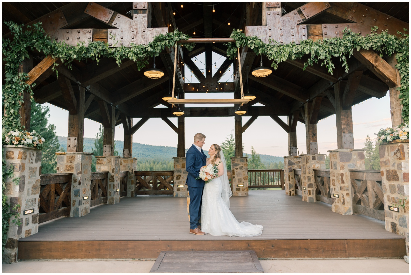 Newlyweds smile at each other while standing under an ornate wooden beam overhang at a swiftwater cellars wedding