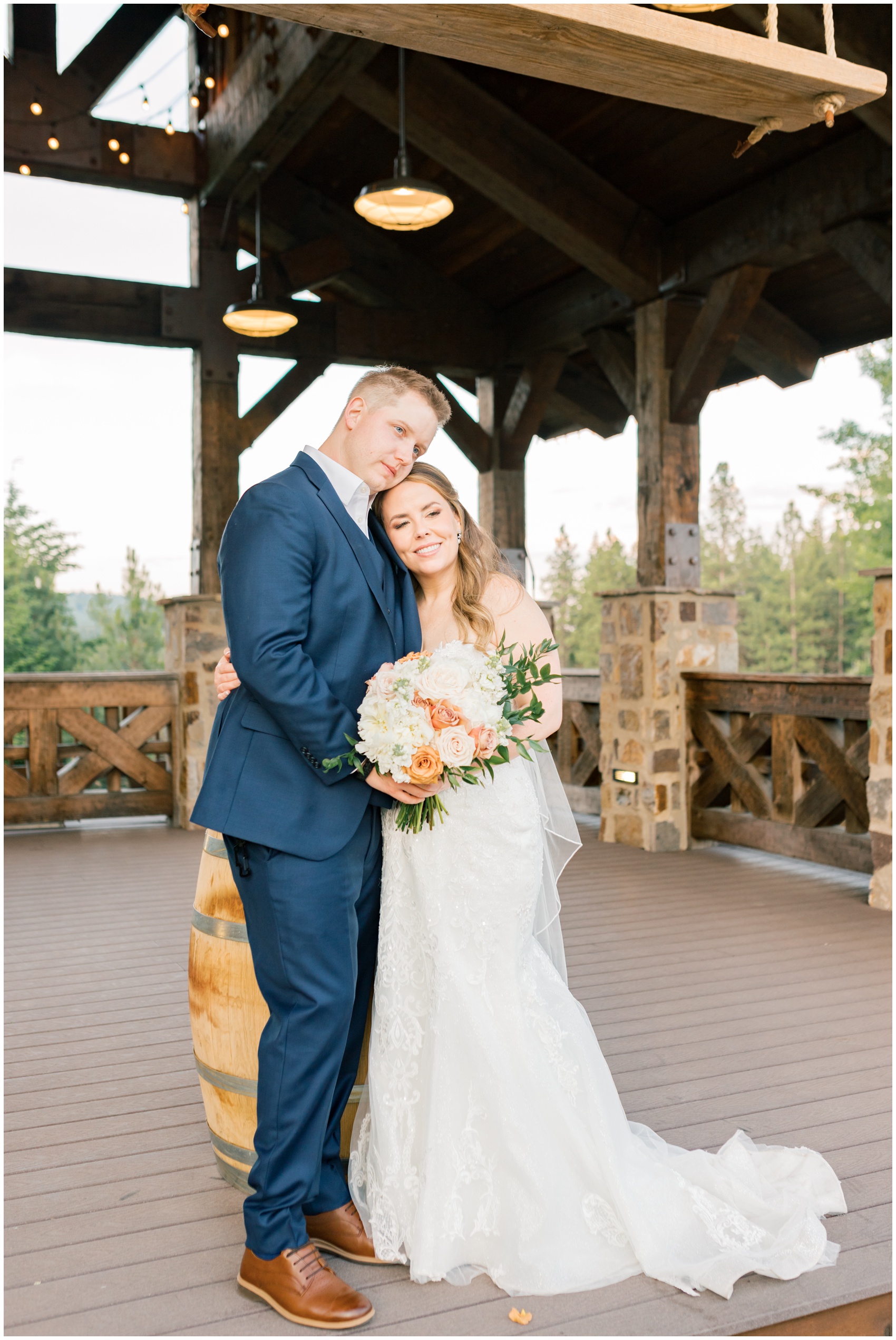 Newlyweds snuggle while standing on a deck