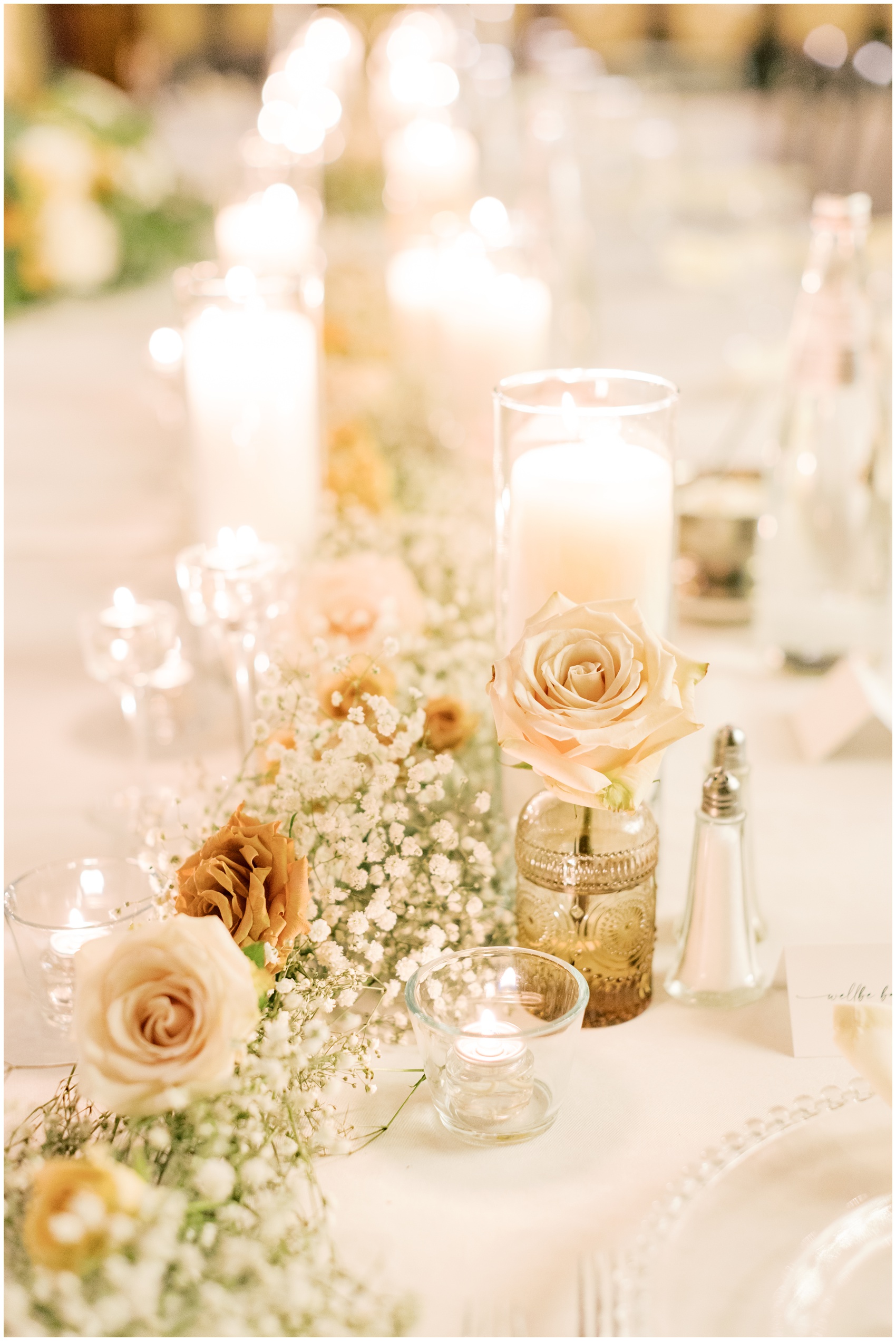 Details of a long table setting with pink roses and candles at a swiftwater cellars wedding reception