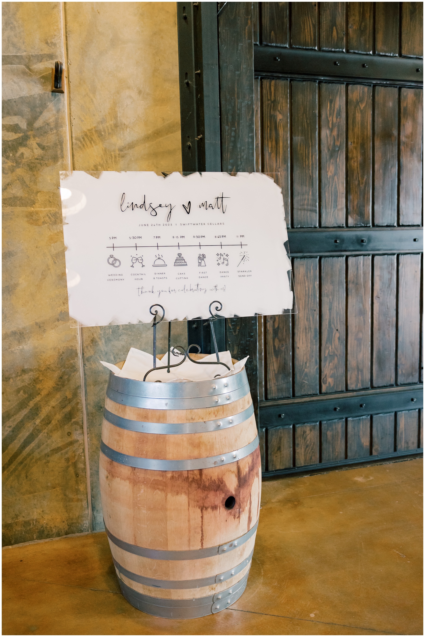 Details of a wedding reception sign and schedule standing on a wine barrel