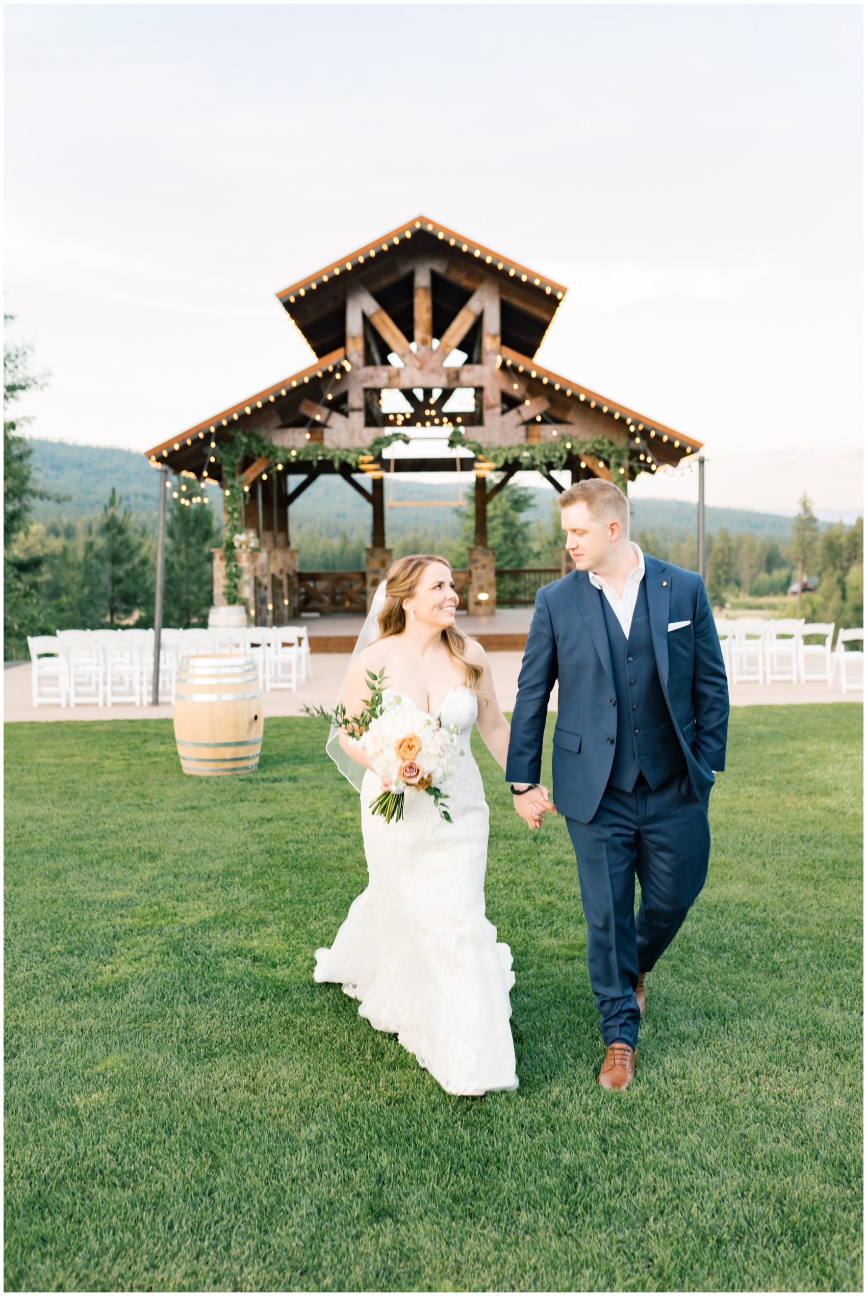 A bride and groom walk hand in hand away from the ceremony location at their swiftwater cellars wedding