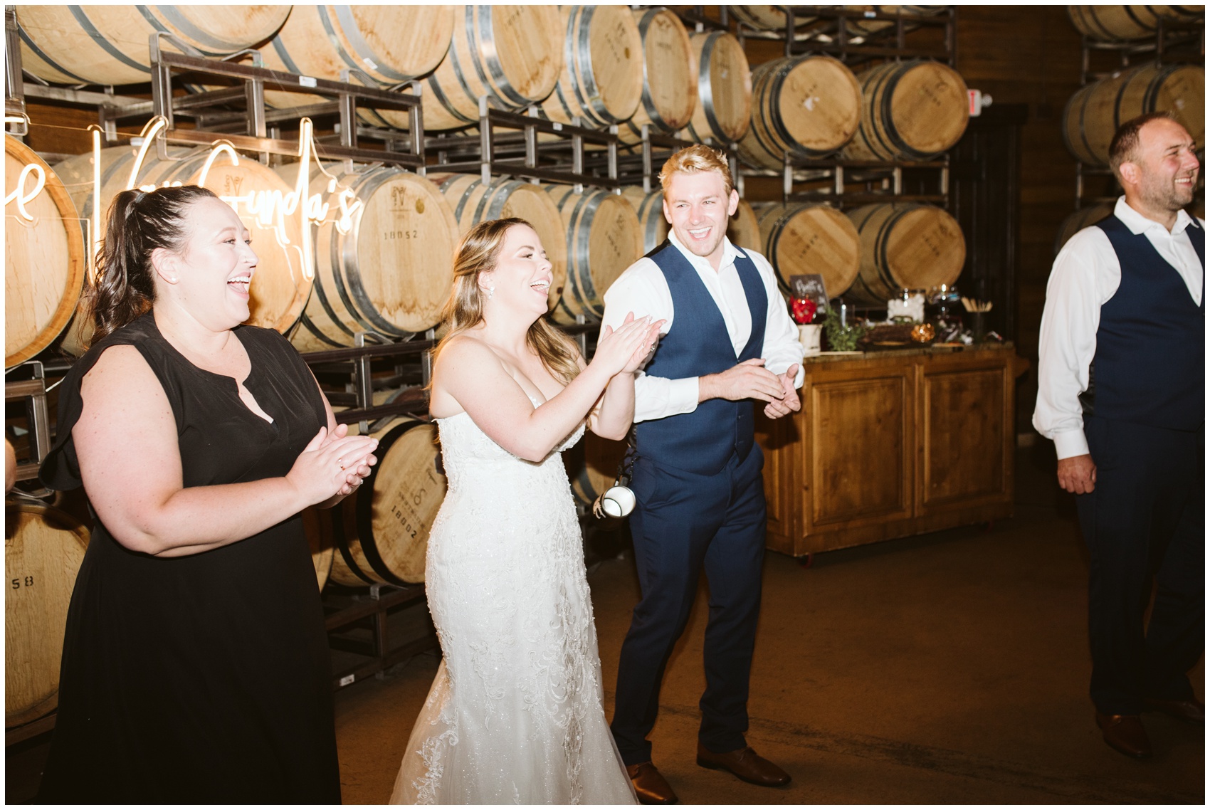 Newlyweds celebrate and laugh in front of wine barrels at their swiftwater cellars wedding reception