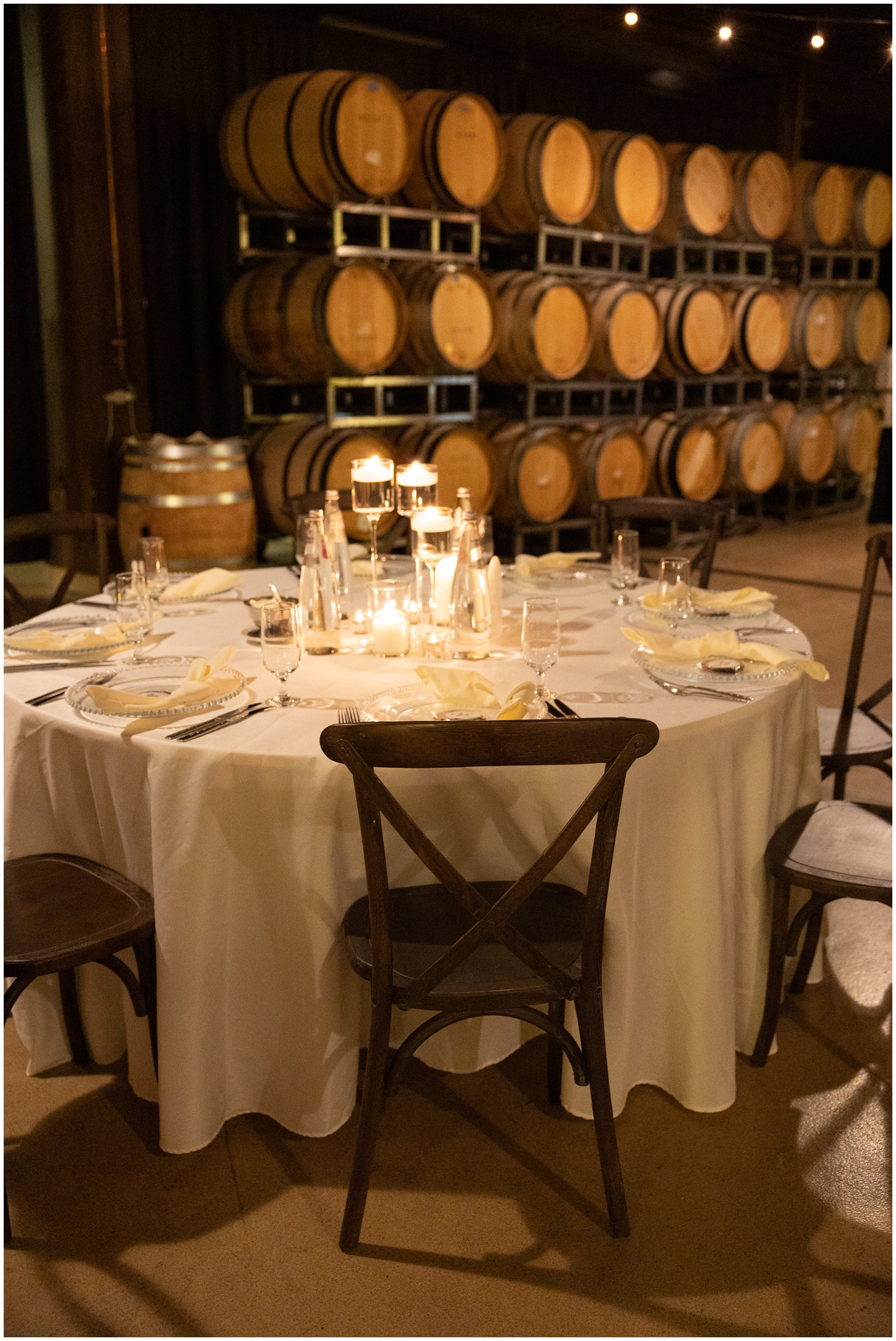 A round table set up with candles near wine barrels at a swiftwater cellars wedding