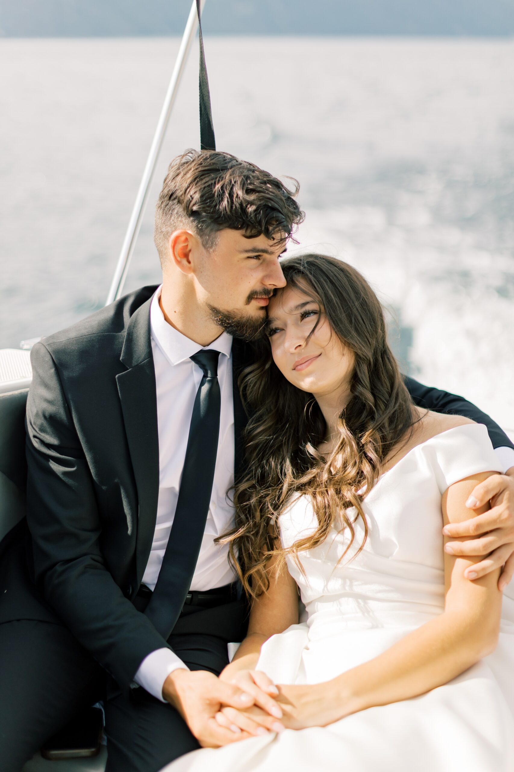 Newlyweds cuddle in the back of a boat at sunset while exploring their Hayden Lake wedding venues