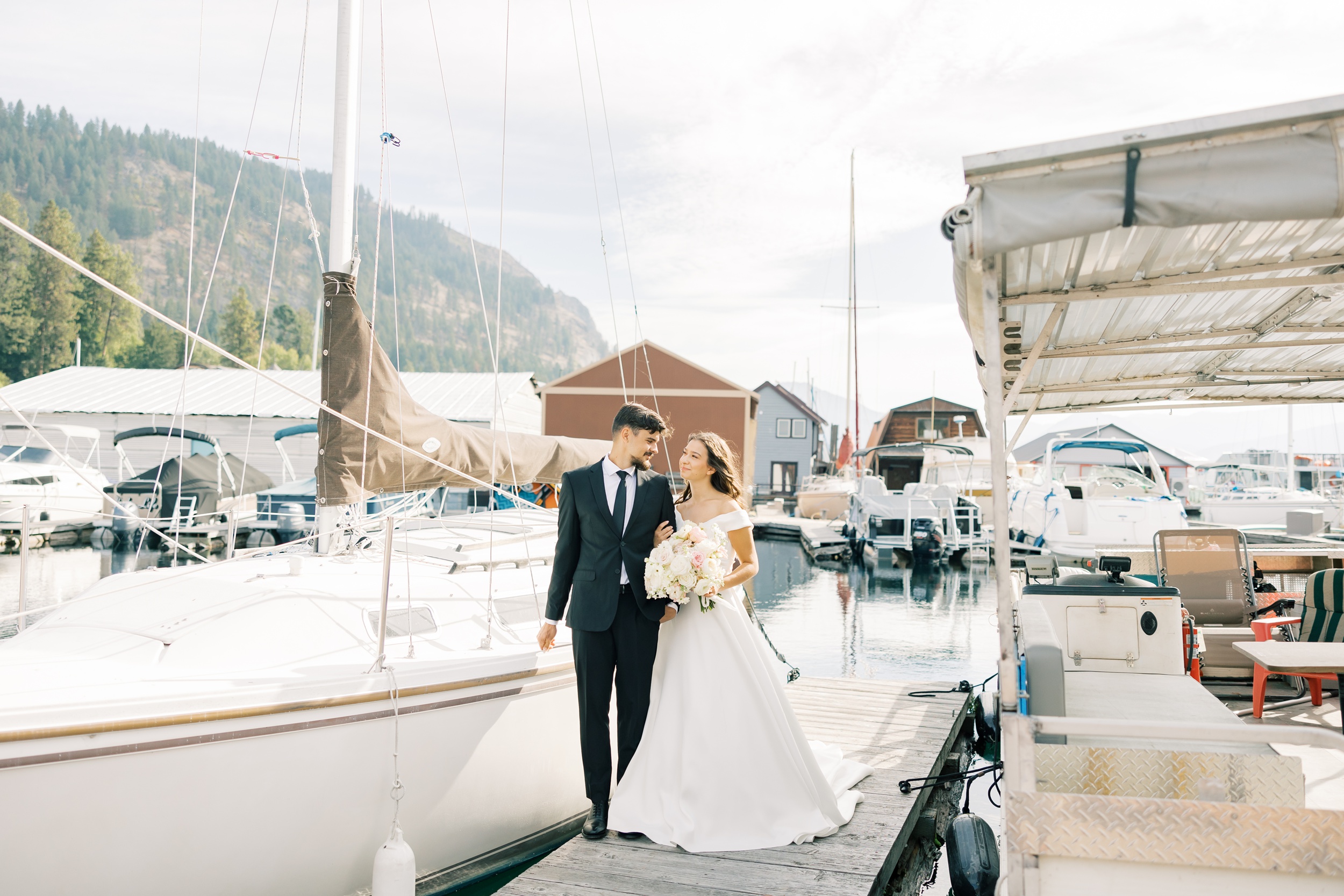 A bride and groom walk through a marina arm in arm at one of the stunning Hayden Lake wedding venues