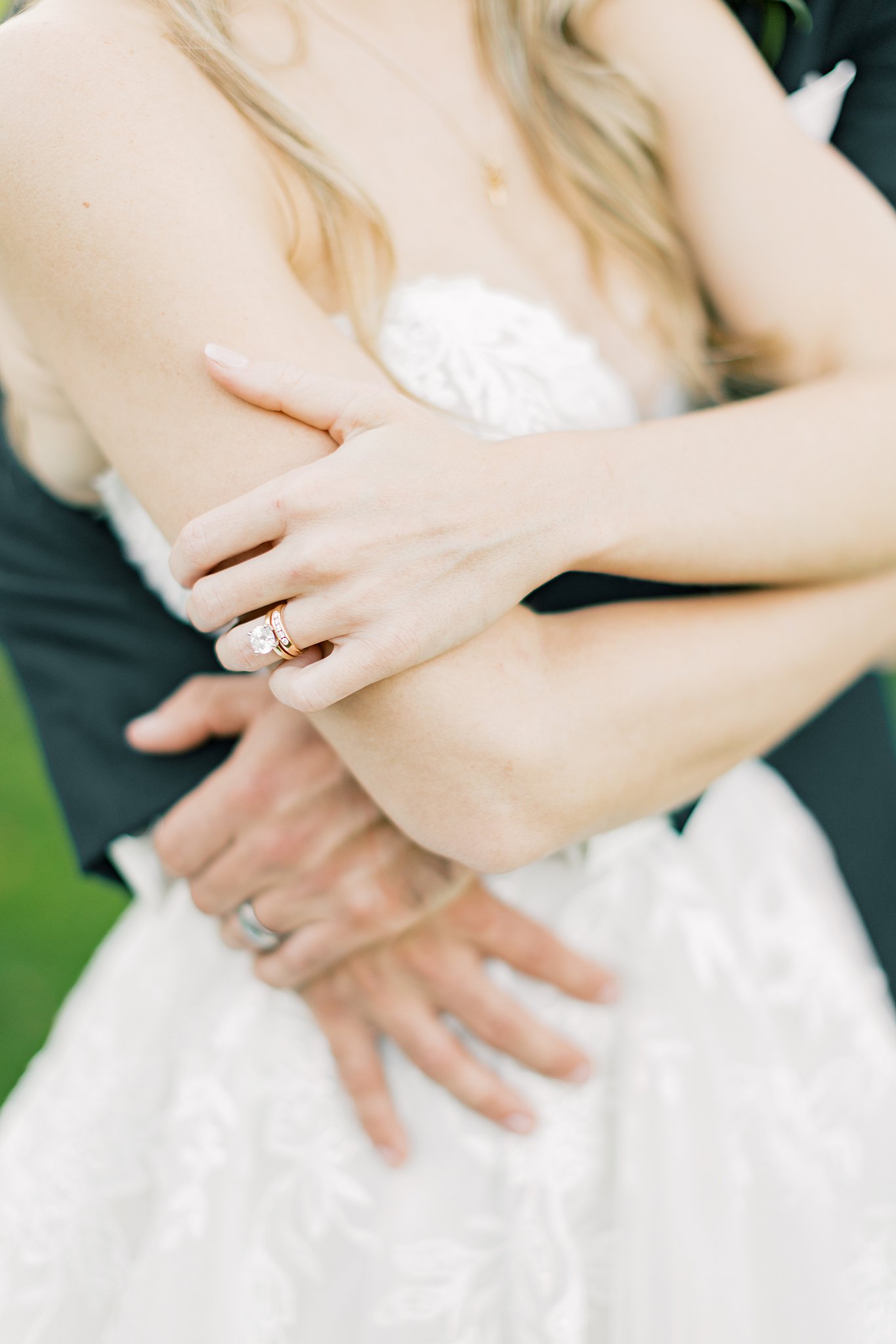 Details of a bride's ring hand as she is hugged from behind