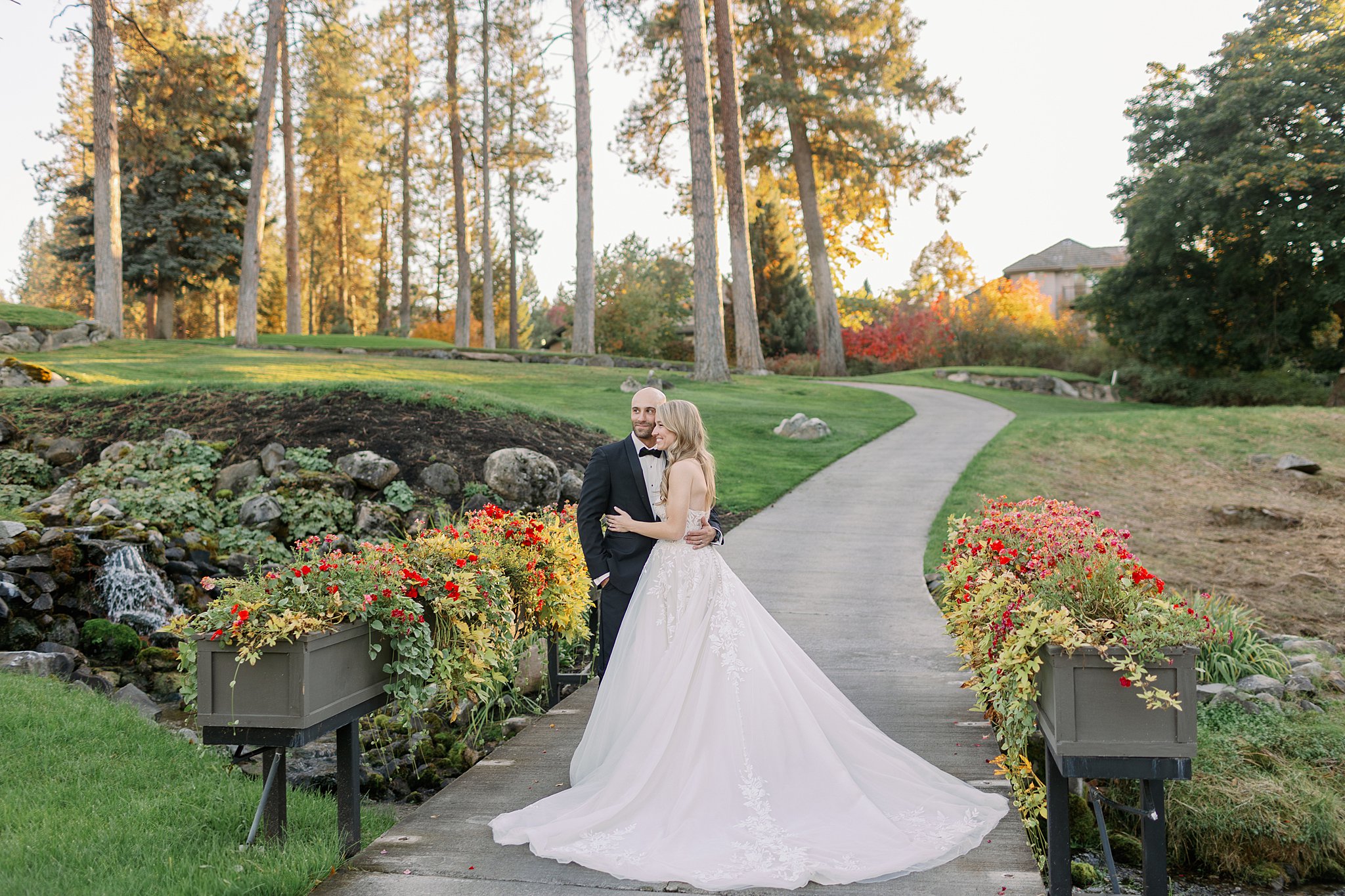 Newlyweds snuggle with arms around each other in a garden trail at sunset at their Kalispel Country Club Wedding