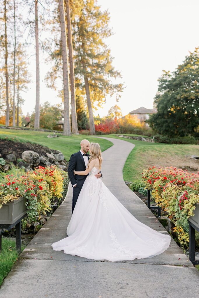 Newlyweds snuggle on a garden sidewalk touching noses and hugging at sunset at their Kalispel Country Club Wedding