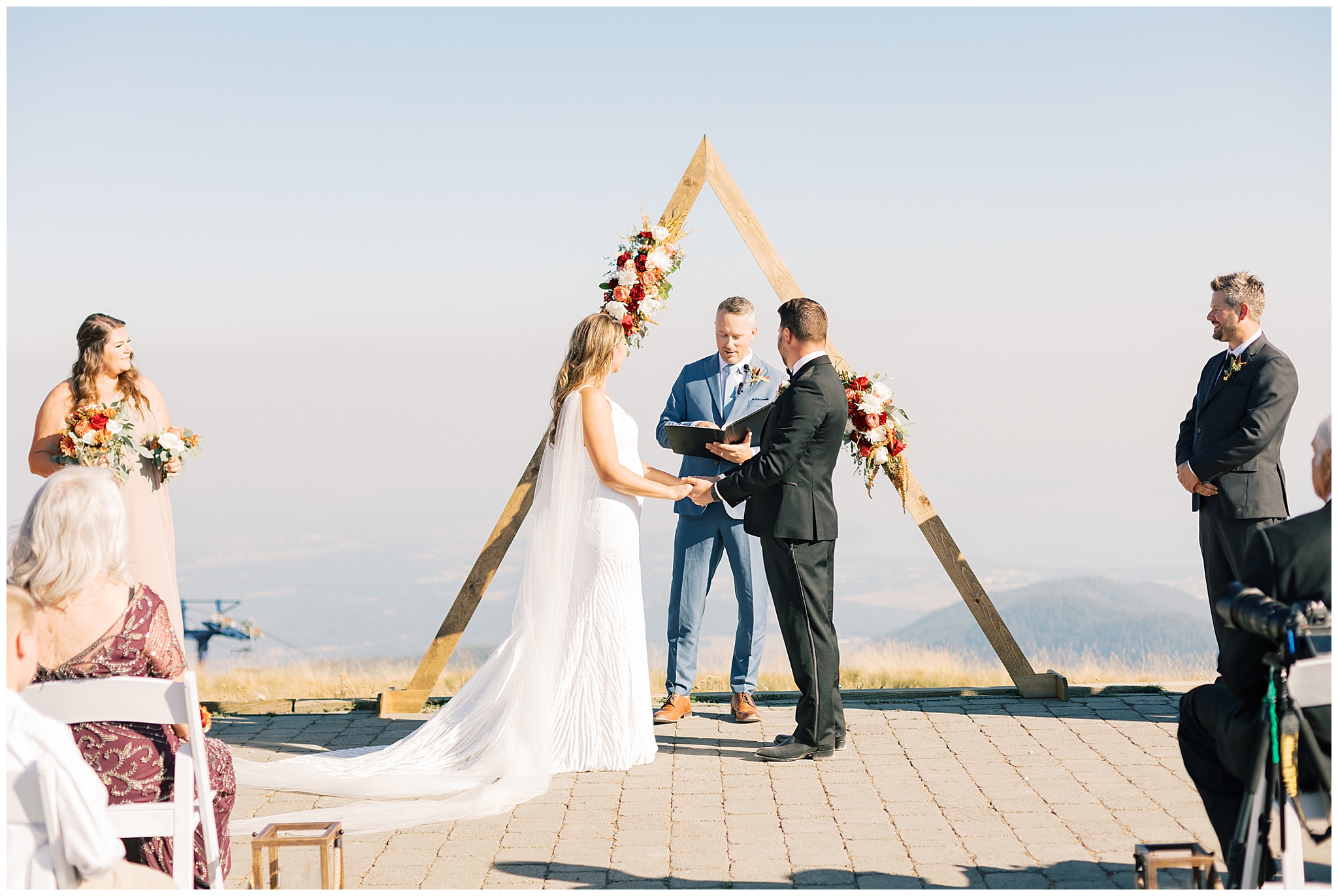 Newlyweds stand under their triangle wooden arbor at an epic vista for their Schweitzer Mountain Wedding