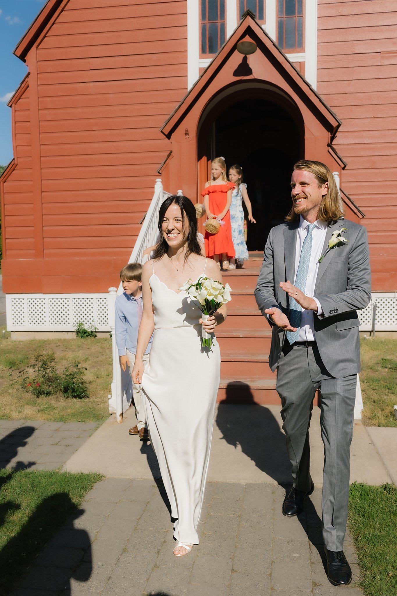 Newlyweds exit the fort sherman chapel while smiling and clapping with their guests