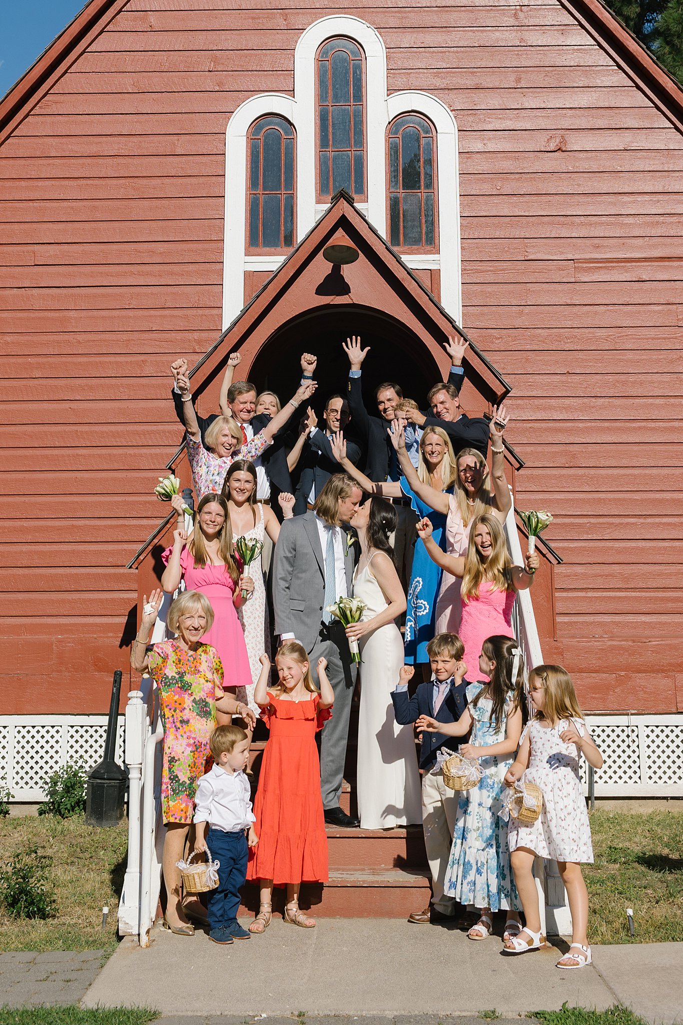 Newlyweds kiss on the fort sherman chapel steps with their guests cheering with arms up