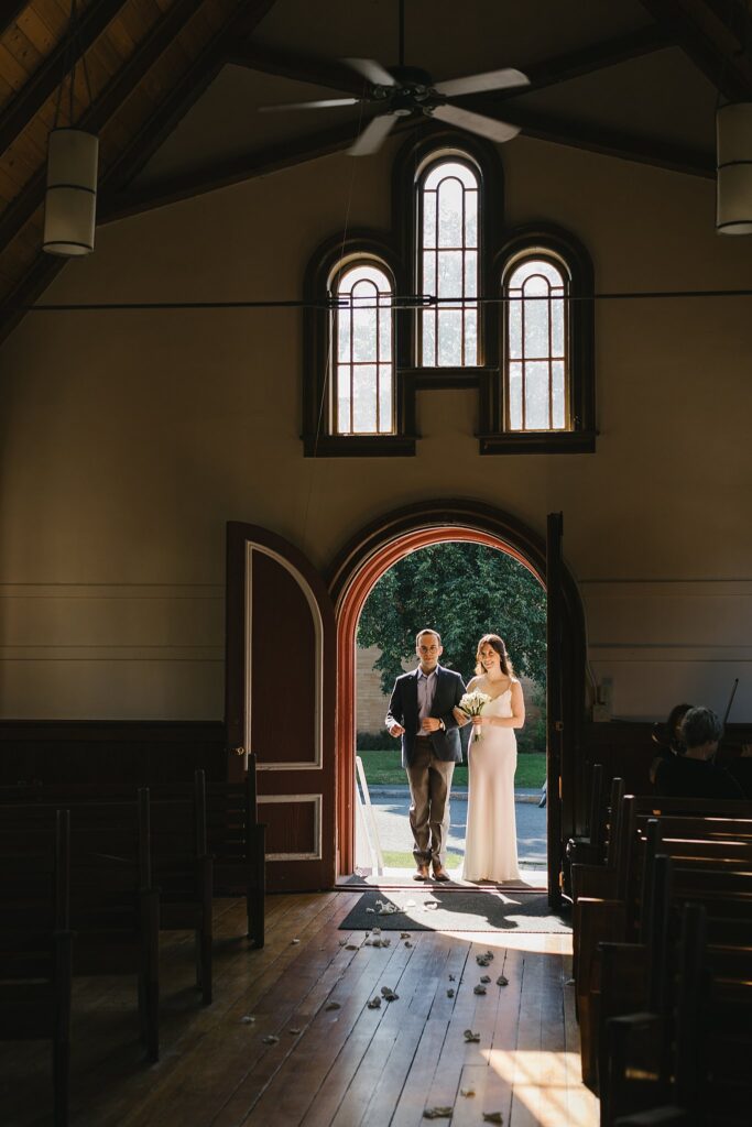 A bride enters the fort sherman chapel with her male relative escorting her