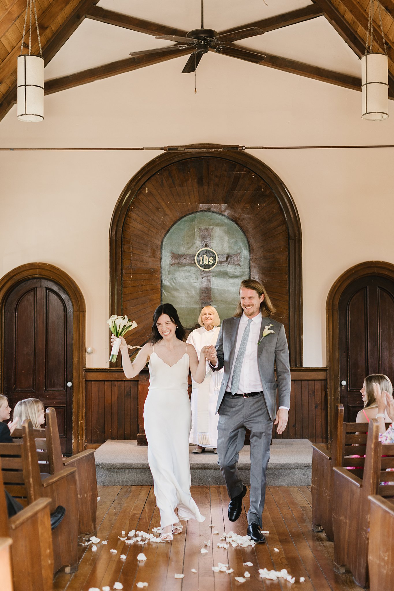 A bride and groom hold hands and walk up the aisle to finish their fort sherman chapel ceremony