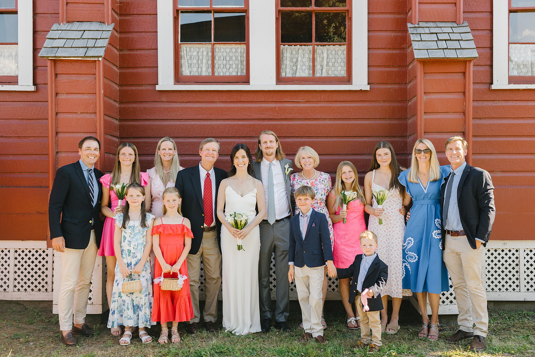 Newlyweds stand and smile with a large family outside the fort sherman chapel