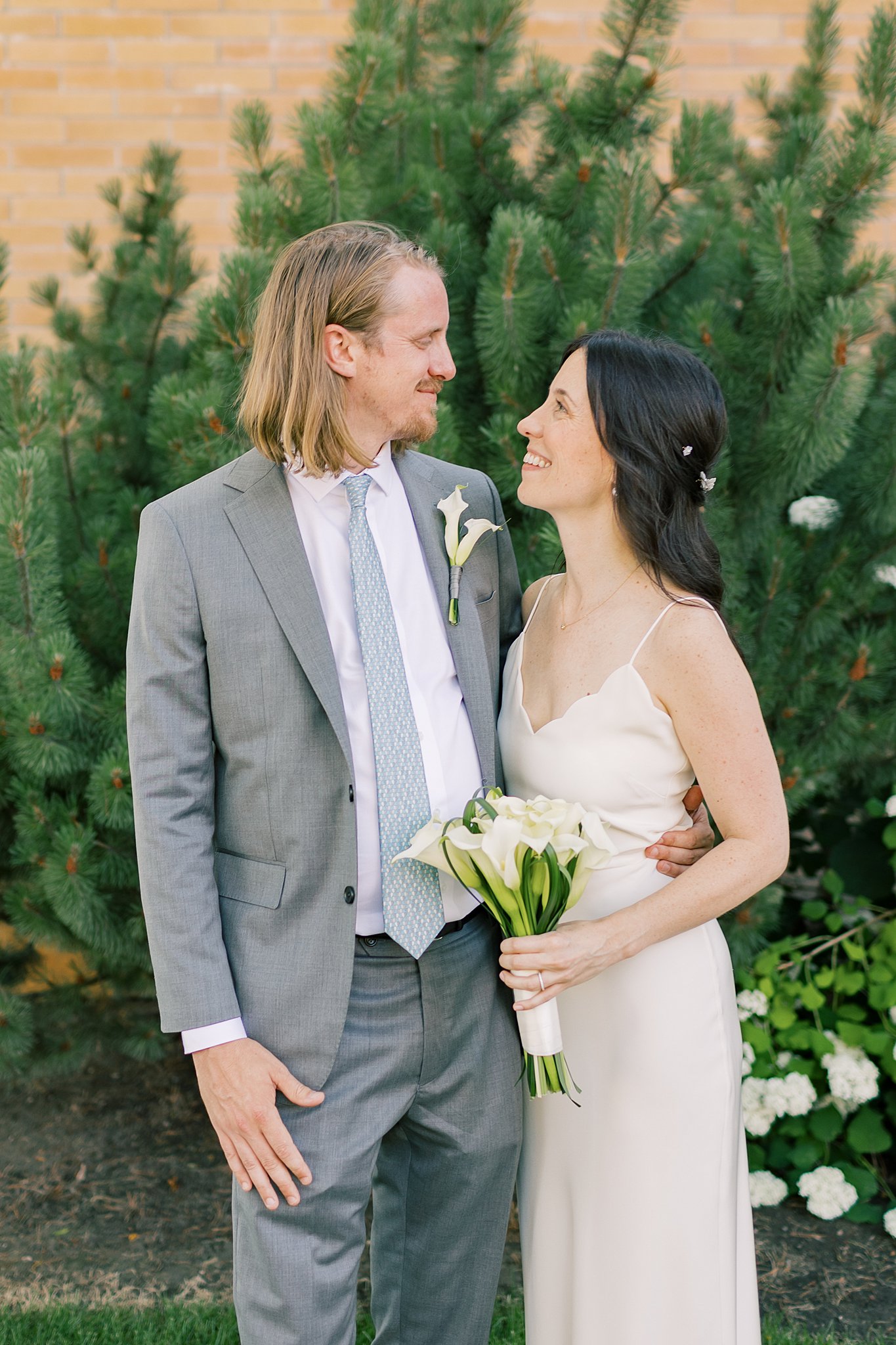 Newlyweds smile at each other while hugging in a garden