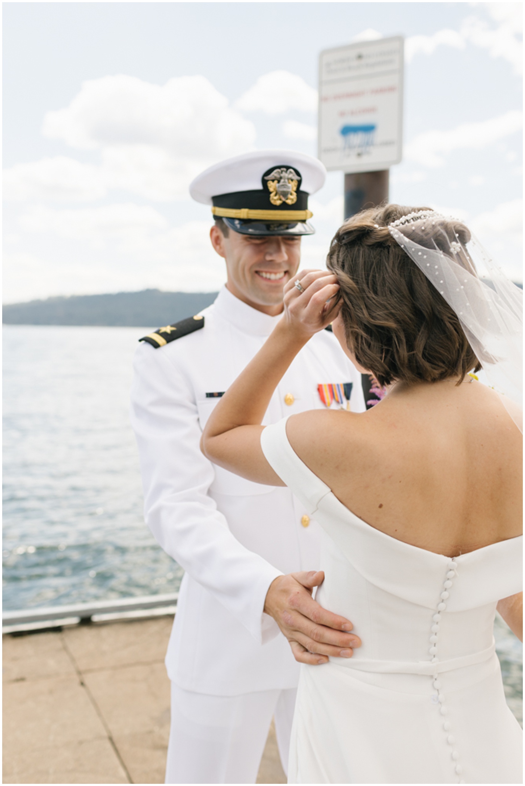 A military man smiles big while seeing his bride for th first time on a dock