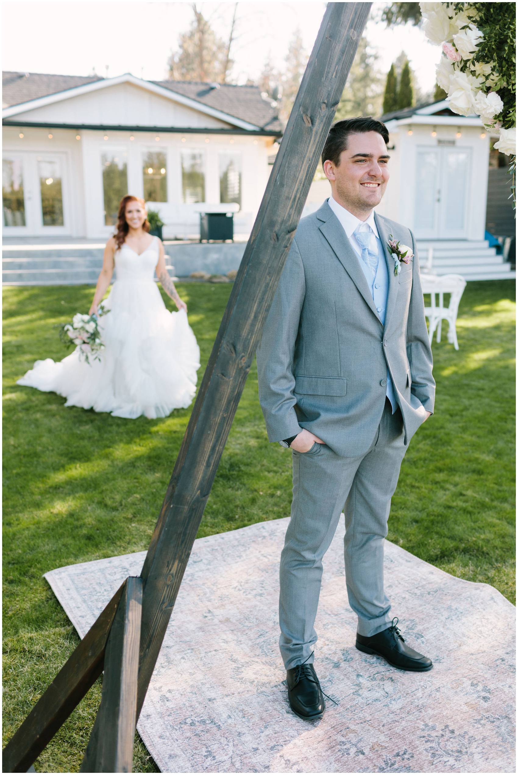 A groom decided between first look vs first touch as he waits in a lawn as his bride approaches from behind