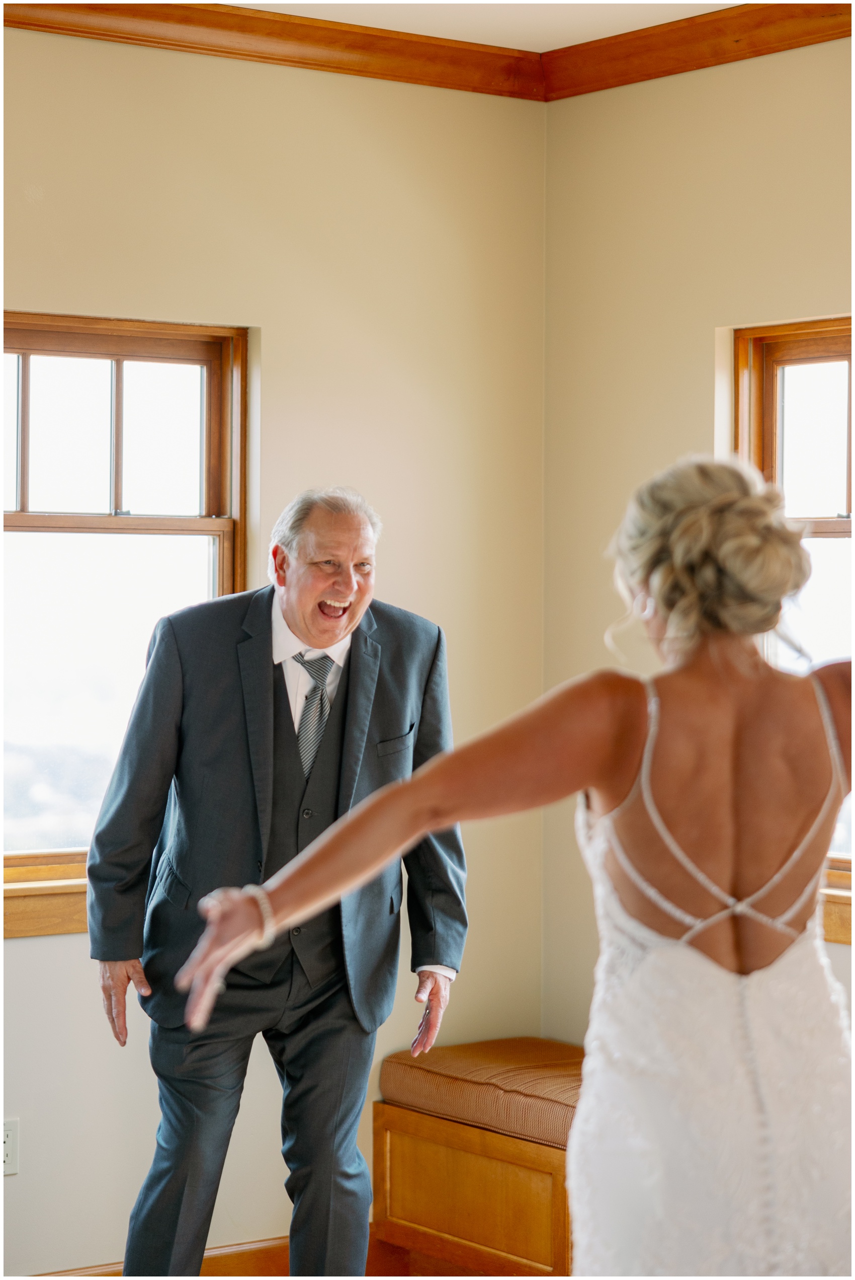 A happy dad smiles big while seeing his daughter in her wedding dress for the first time