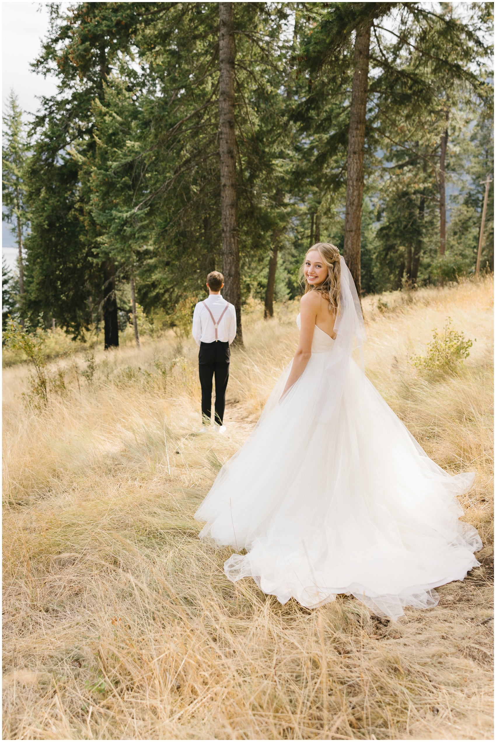 A bride smiles over her shoulder while walking towards her groom waiting for her first look vs first touch