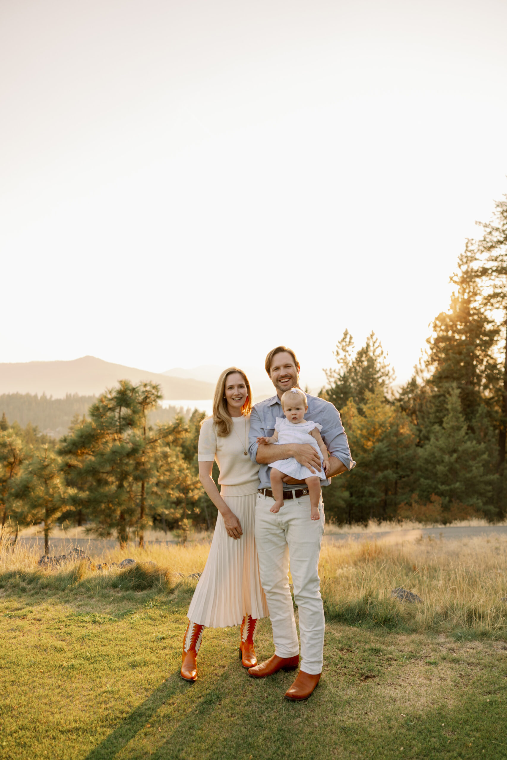 A beautiful family of three is standing with the picturesque views at Gozzer Ranch Club in Idaho