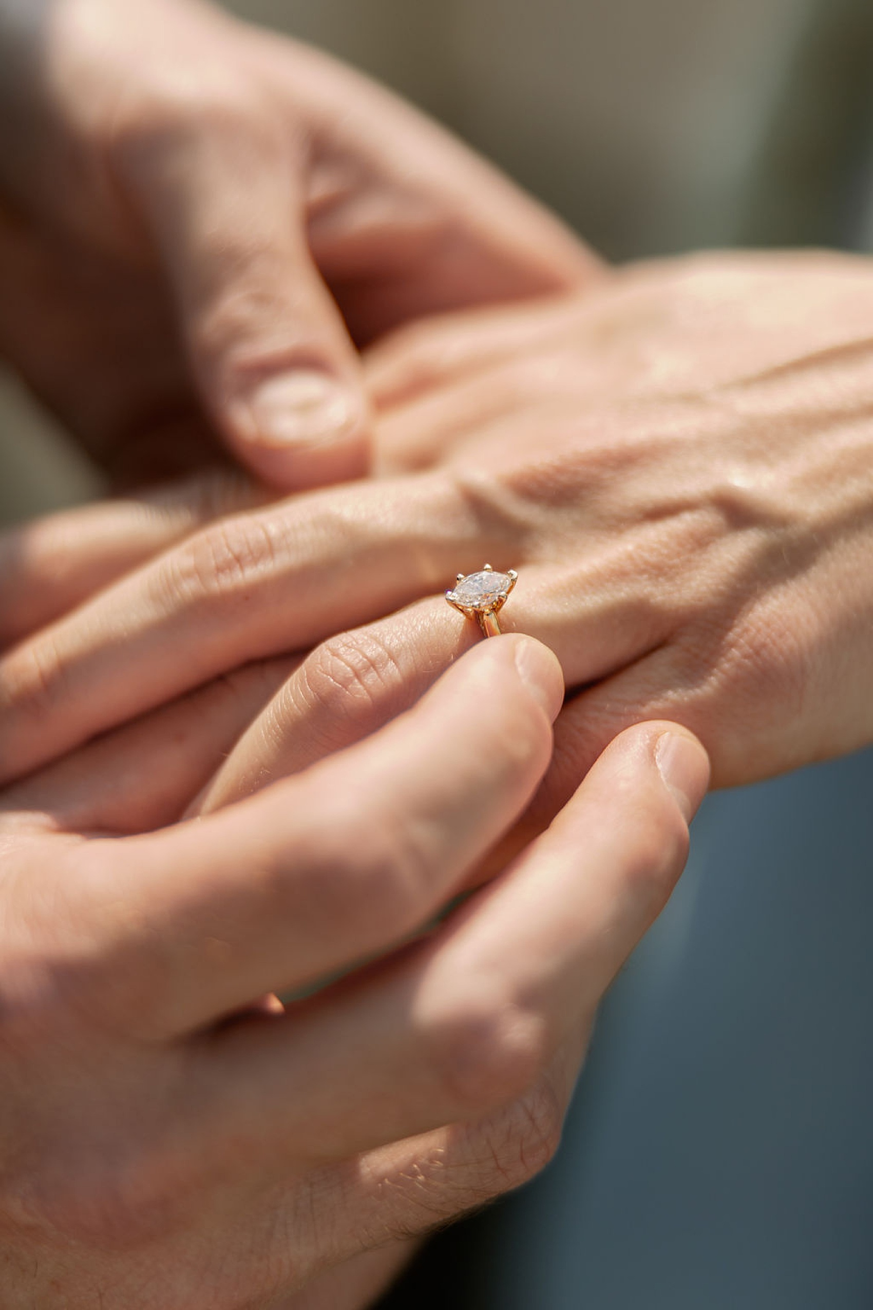 Details of a man putting an engagement ring on his fiancee's finger